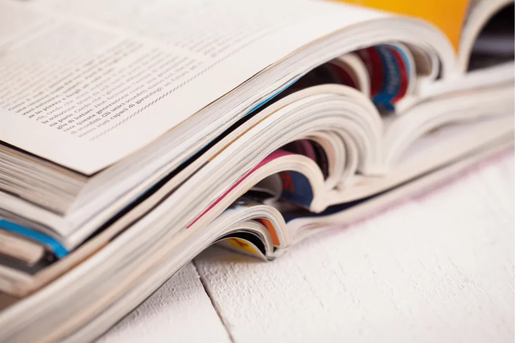 Stos kolorowych magazynów i gazet, ilustrujący jak efektywnie uczyć się języka z artykułów prasowych i autentycznych materiałów w SpeakPro Academy.