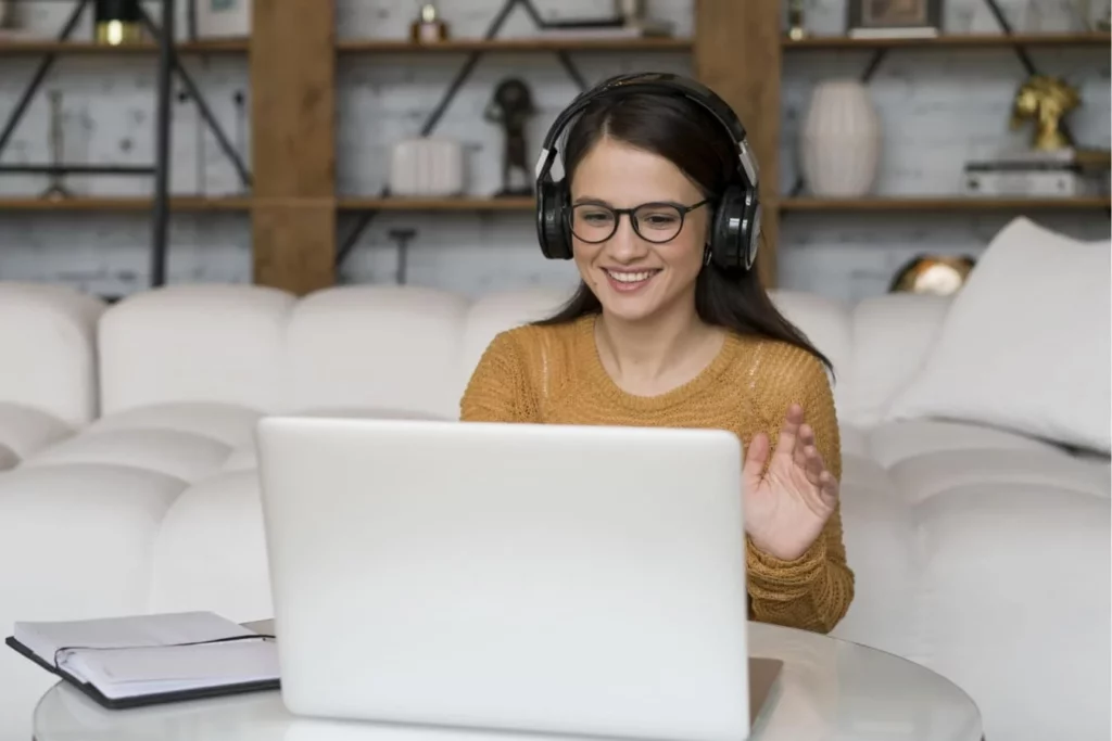 Kursantka w słuchawkach witająca się z lektorem podczas zajęć wideo - motywująca nauka języka obcego online w SpeakPro Academy.