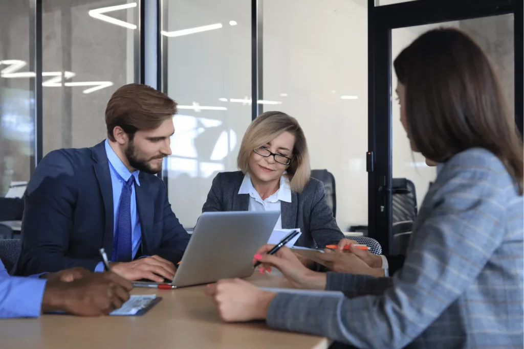 Trójka profesjonalistów podczas spotkania rekrutacyjnego w biurze - praktyczna nauka Business English i przygotowanie do wyzwań zawodowych w obcym języku.