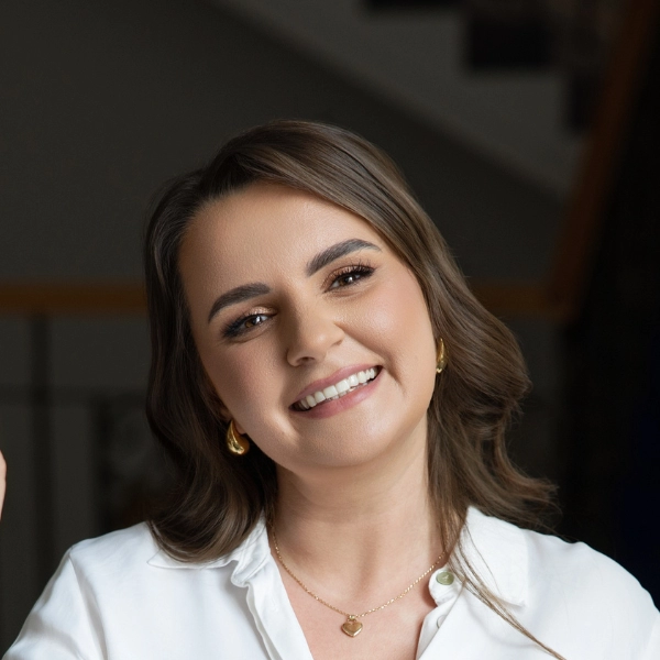 Uśmiechnięta Monika O., właścicielka szkoły językowej SpeakPro Academy i lektor języka angielskiego, podczas pracy przy laptopie.